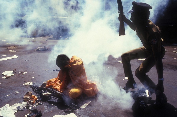 Sri Lanka. Monk seated on the ground surrounded by tear gas. Pettah bus stand, Colombo, 28th July 1987. Protest at the signing of the Indo Lanka Peace Accord between India and Sri Lanka.